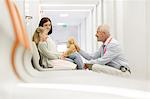 Doctor with teddy bear talking to girl patient in clinic corridor