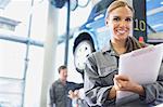 Portrait smiling mechanic with clipboard in auto repair shop