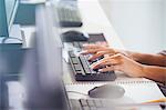 Student typing on computer keyboard in adult education classroom