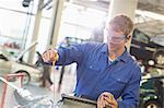 Mechanic checking engine oil in auto repair shop