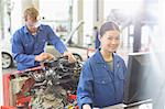 Portrait smiling female mechanic at computer in auto repair shop