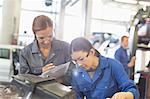 Female mechanics working on engine in auto repair shop