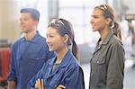 Smiling mechanics looking away in auto repair shop