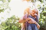 Grandmother hugging granddaughter on swing