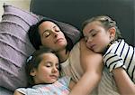 Serene mother and daughters napping on sofa