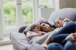 Serene mother and daughters napping on living room sofa