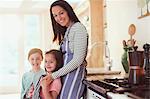 Portrait smiling mother and daughters in kitchen