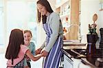 Mother and daughters holding hands in kitchen