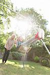 Grandmother pushing carefree granddaughter on swing in backyard