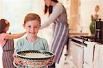 Portrait smiling girl baking holding bowl of flour in kitchen