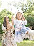 Mother in dress pushing daughter on swing in backyard