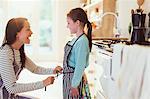 Mother tying apron on daughter in kitchen