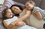 Affectionate mother and daughters cuddling on sofa