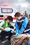 Rescue workers performing CPR and preparing manual resuscitator over car accident victim