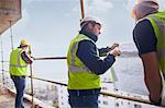 Construction worker and engineer reviewing blueprints at highrise construction site