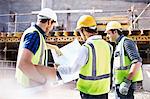 Construction workers and engineer reviewing blueprints at construction site