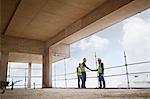 Construction workers handshaking at highrise construction site