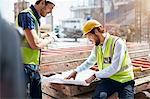 Construction worker and engineer reviewing blueprints at construction site