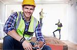 Portrait smiling construction worker with cell phone at construction site