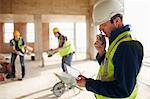 Foreman with digital tablet using walkie-talkie at construction site