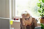 Stressed woman with hands in hair working in office