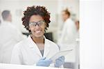 Scientist smiling in laboratory, colleagues working in background