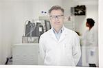 Scientist smiling in laboratory, colleague working in background