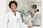 Scientist smiling in laboratory, colleagues working in background