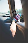 Leg with colourful striped socks on car window