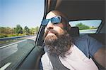 Bearded man looking out of car window on highway, Garda, Italy