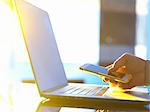 Business man at laptop computer with smartphone in office with sunlight coming through window