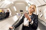 Businesswoman texting on escalator, London Underground, UK