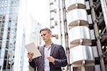 Businessman using digital tablet in street, London, UK