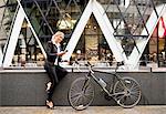 Businesswoman with bike outside 30 St Mary Axe, London, UK