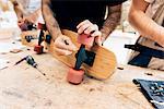 Cropped view of young men in workshop attaching wheels to skateboard