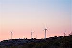 Wind turbines on mountain top against dramatic orange sky, Castelsardo, Sardinia, Italy