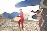 Group of surfers on beach, carrying surfboards