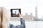 Rear view of young woman photographing Big Ben on digital tablet, London, England, UK