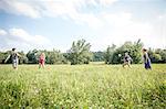 Group of young adults playing badminton in field