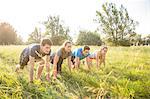 Group of friends in field, in starting position, about to race