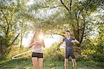 Young couple in rural environment, using hula hoops