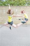 Young women jumping in front of concrete wall