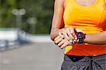 Cropped shot of young female runner setting smartwatch in parking lot