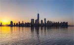 Silhouetted view of Manhattan financial district skyline at sunset, New York, USA