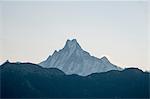 Snow capped mountain peak against dark mountain range, Nepal