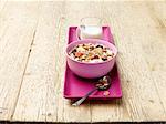 Breakfast bowl of muesli with fruit and milk on wood