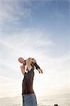 Mature man lifting up his toddler daughter on beach, Calvi, Corsica, France