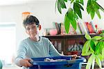 Mature woman carrying laundry basket looking at camera