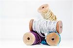 Stack of wooden reel with sparkly silver, gold, blue and purple ribbons