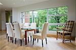 Glass dining table and leather chairs in front of large window in modern dining room